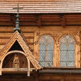 Detale drewnianej kaplicy. Zdobione okno i drewniana figurka Chrystusa pod daszkiem.