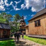 Widok na grupę turystów pośród drewnianych zabudowań Muzeum Orawski Park Etnograficzny w Zubrzycy Górnej.