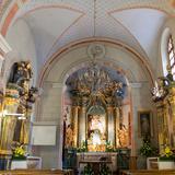 Wnętrze jasnego, wąskiego kościoła z stropem z łukami, częściowo malowanym w gwiazdki, z obrazami na ścianach, z amboną po lewej i ołtarzem głównym na wprost. Po lewej stronie ołtarza obraz Pana Jezusa.