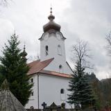 Biała wieża kościelna z zegarem i cebulastym hełmem.