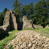 Ruiny zamku, fragmenty ścian z kamienia i gruzowisko.