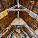 Drewniany dach, widziany z wnętrza budynku. Do dachu przyczepione drewniane tablice z płaskorzeźbami oraz tekstami.