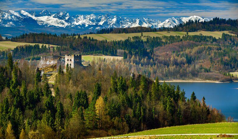 Widok na wzgórze z zamkiem w Czorsztynie, Tatrami w tle i fragmentem Jeziora Czorsztyńskiego.