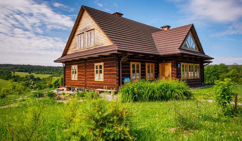 Drewniany jednopiętrowy dom ze spadzistym dachem i zagospodarowanym poddaszem