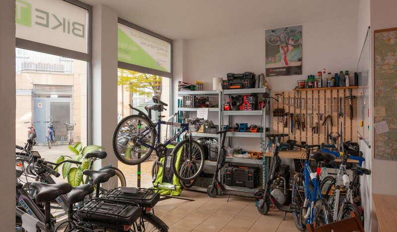 Wnętrze wypożyczalni, kilka rowerów i półka z akcesoriami rowerowymi.