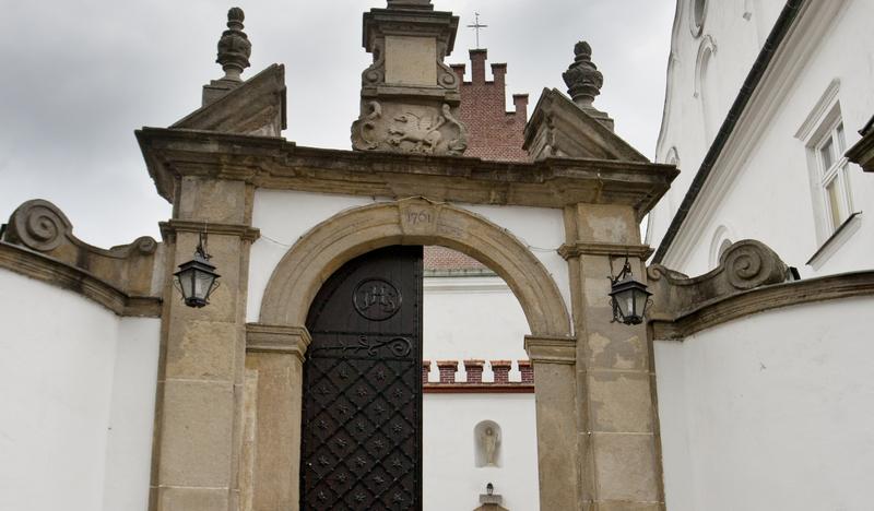 Brama klasztoru cystersów tynkowano na biało z kamiennymi elementami, nad bramą figura świętego.